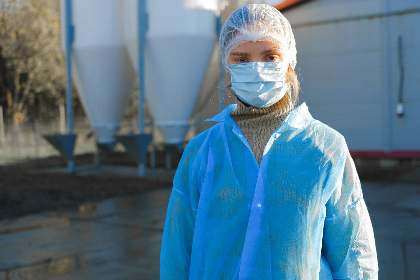 Processing-plant technician in protective clothing and a respirator, focused on the line.